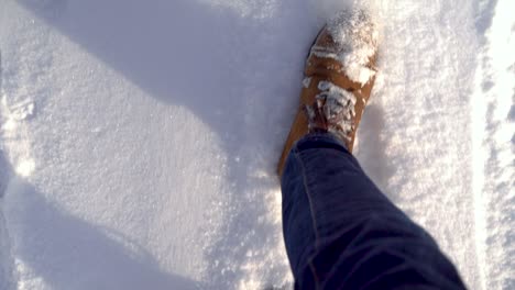 POV-looking-down-on-male-feet-walking-through-fresh-powder-snow-slow-motion