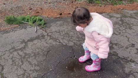 A-cute-little-girl-jumping-in-a-puddle-then-running-away-wearing-pink-rubber-boots