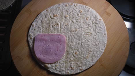 Putting-ham-and-cheese-seperat-on-tortilla-with-left-hand-and-correcting-the-cheese-layout