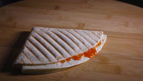Laying-two-quarter-tortillas-with-orange-sauce-on-a-wooden-table