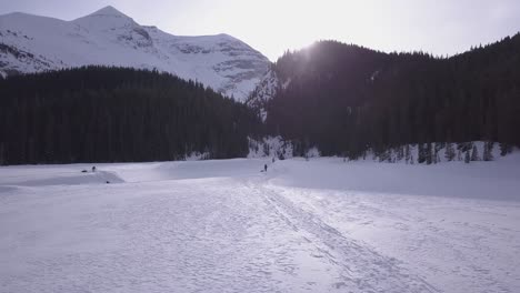 Expedition-skiers-cross-half-frozen-river-at-foot-of-Rocky-Mountains