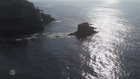 Aerial-to-sea-stack-islands-in-calm-Pacific-Northwest-ocean-sun-beam