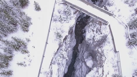 Aerial:-Snowy-bridge-crosses-deep-winter-Marble-Canyon-in-Rocky-Mtns