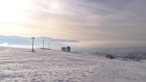 Fast-pan-over-wide-open-snow-landscape-with-town-in-distance