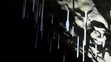 Hollow-soda-straws-and-a-carrot-drip-water-from-ceiling-of-dark-cave
