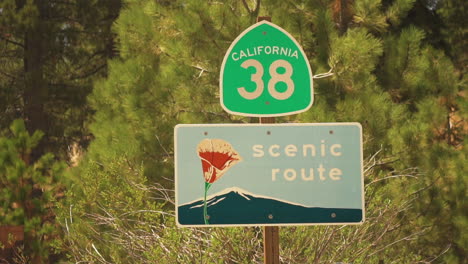Close-up-view-of-scenic-route-sign-below-green-California-route-number-38-signboard-while-heading-towards-Pleasant-Valley,-California,-USA