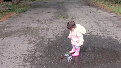 A-little-girl-jumping-and-dancing-in-a-puddle-wearing-pink-rubber-boots