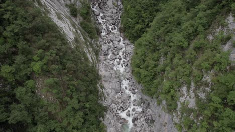Video-Einer-Flachen-Drohnenansicht-Eines-Beschreibenden-Frontalen-Vogels-über-Dem-Fluss-Der-Boka-Cascasa-Und-Der-Cascaca-Am-Horizont-In-Slowenien