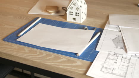 Workspace-of-architect-on-wooden-table-with-plans-and-blueprints