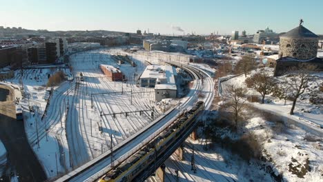 Train-Passing-by-Medieval-Tower,-Snow-Covered,-Gothenburg,-Sweden-Aerial