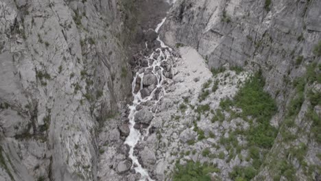 Video-of-a-flat-drone-view-of-a-descriptive-ascending-bird-over-the-river-of-the-Boka-cascasa-and-the-cascaca-on-the-horizon-in-Slovenia