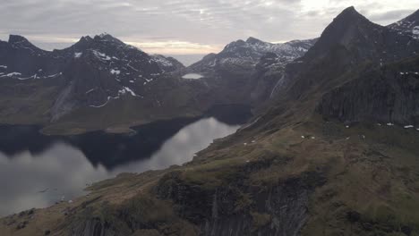 Aerial-view-of-the-Reinefjord-and-mountains-of-the-Lofotodden-Nasjonalpark,-cloudy-fall-day,-in-Lofoten,-Norway---pan,-drone-shot