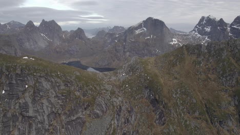 Aerial-view-high-above-mountains-of-the-Lofotodden-Nasjonalpark,-autumn-overcast-in-Lofoten,-Norway---pan,-drone-shot