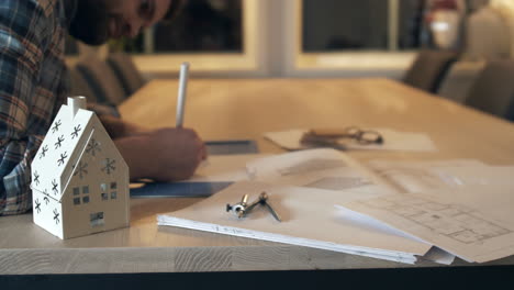 Architect-using-pencil-and-paper-to-create-blueprints-on-wooden-desk