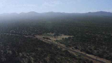 Panorama-Aéreo-De-Una-Granja-Y-Un-Huerto-En-Un-Desierto-Mexicano-Con-Fondo-De-Montaña