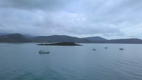 Drone-flying-on-an-overcast-day-towards-a-small-Island-off-the-coast-of-Airlie-Beach,-Shute-harbour,-North-Queensland