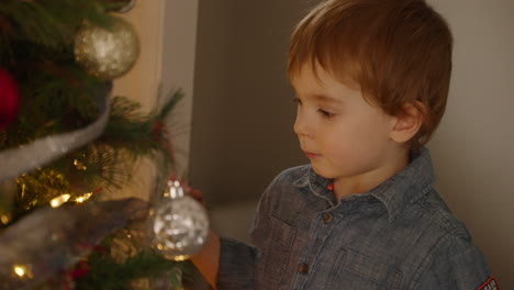 Toddler-boy-playing-with-ornaments-on-a-Christmas-tree