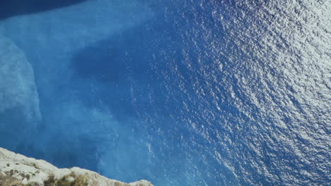 Looking-down-massive-cliff-face-at-emerald-blue-water-on-Zakynthos-Greece