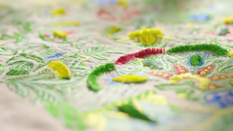 Close-up-pan-shot-of-colorful-sewed-pattern-on-table-cloth-in-fabric