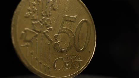 Close-up-of-a-50-euro-cent-coin-with-a-black-background-that-is-spinning