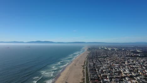 Luftaufnahme-Von-Manhattan-Beach-In-Kalifornien-Unter-Strahlend-Blauem-Himmel-Mit-Küstenhäusern-Entlang-Der-Sandigen-Strecke