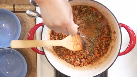 Adding-red-hot-cayenne-pepper-powder-to-the-roux-sauce-for-a-spicy-gumbo---overhead-view-slow-motion-GUMBO-SERIES