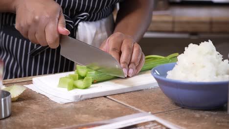Chopping-organic-celery-to-add-to-a-homemade-recipe---side-view-slow-motion-GUMBO-SERIES