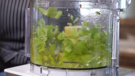 Mincing-chopped-celery-in-a-food-processor-by-pulsing-the-on-off-button---slow-motion-side-view-GUMBO-SERIES