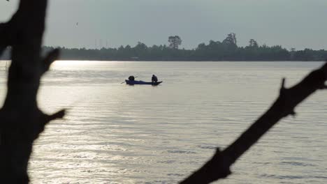 Eine-Abstrakte-Silhouettenaufnahme-Eines-Lokalen-Thailändischen-Fischers,-Der-An-Einem-Schönen-Morgen-Am-Fluss-Chanthaburi,-Thailand,-über-Dem-Bug-Seines-Bootes-Kauerte-Und-Ein-Fischernetz-Vorbereitete