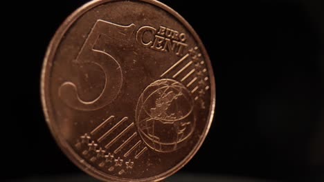 Close-up-of-a-5-euro-cent-coin-with-a-black-background-that-is-spinning