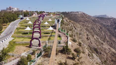 Aerial-drone-view-over-a-suspension-bridge,-towards-the-top-of-Raghadan-Forest-Park,-in-Saudi-Arabia