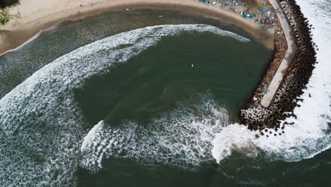 Menschen-Surfen-Am-Strand-Von-Sealinks,-Während-Große-Wellen-Am-Strand-Rollen-Und-An-Den-Wellenbrechern-In-Vietnam-Zerschmettern