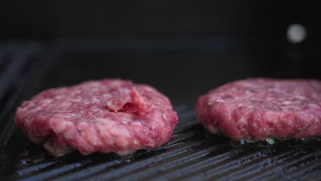 Slow-pan-to-the-right-of-four-burger-patties-sizzling-on-a-BBQ