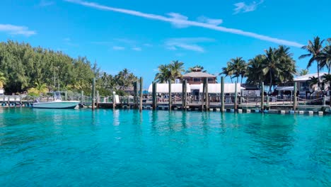 Ankunft-Auf-Der-Blauen-Laguneninsel-Auf-Den-Bahamas-Mit-Dem-Boot-4k-30-Fps-Ruhige-Schwenkaufnahme-Einer-Herrlichen-Schlüsselinsel-Mit-Häusern-Und-Bäumen,-Türkisfarbenem-Wasser