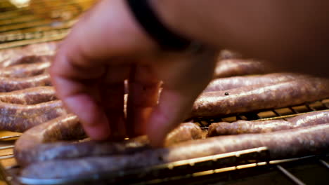 Placing-traditional-farmer's-sausage-on-the-grid,-ready-to-barbecue