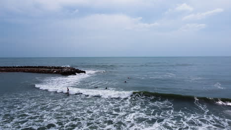 A-slow-zoom-out-from-the-waves-near-the-shore-of-Mui-Ne,-where-a-surfer-is-riding-a-wave