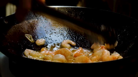 Simmering-shrimp-in-wok-being-stirred-with-tongs