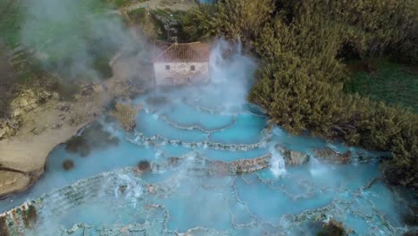The-geothermal-hot-springs-bath-and-waterfall-at-Saturnia,-Tuscany-Italy-close-to-Siena-and-Grosseto-at-sunrise-from-above