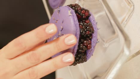 Close-up-of-purple-colored-macarons-with-blueberry-in-the-middle-in-glass-container-on-the-table