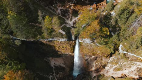 Above-mighty-Pericnik-waterfall-cascade-with-sunshine-forming-rainbow,-aerial