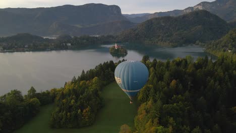 Hot-air-balloon-hanging-above-woodland-hill-with-lake-Bled-in-background