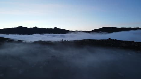 Luftaufnahme-Eines-Wunderschönen-Bergtals,-Das-Nach-Sonnenuntergang-Mit-Nebel-Und-Wolken-Bedeckt-Ist