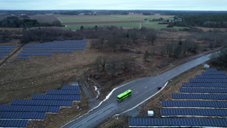 Solar-Park-and-Electric-Bus-on-Highway,-Green-infrastructure-in-Northern-Hemusohere,-Aerial-Reveal