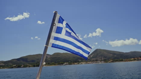 Griechische-Nationalflagge-Weht-Im-Wind-Mit-Meer-Und-Küste-Im-Hintergrund
