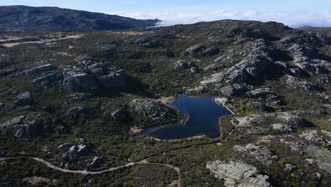 Aerial-view-orbiting-around-a-small-lake-up-high-in-the-mountain-at-Serra-da-Estrela-Portugal