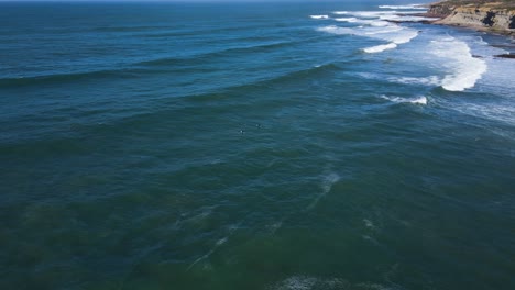 Luftaufnahme-Von-Drei-Surfern-Im-Wasser,-Die-Auf-Die-Perfekten-Wellen-In-Ribeira-De-Ilhas,-Ericeira-Warten
