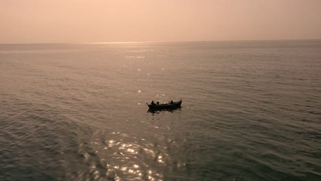 Luftaufnahme-Traditionelles-Ruderboot,-Das-Im-Arabischen-Meer-Gegen-Orangefarbenen-Sonnenuntergangshimmel-Schwimmt