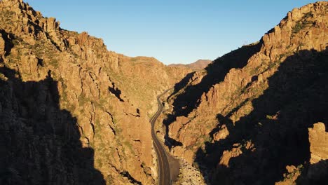 4K-Aerial-of-a-drone-flying-over-a-winding-road-in-between-the-mountains-in-Superior-Arizona-at-golden-hour-east-of-Queen-Creek-tunnel-on-highway-60