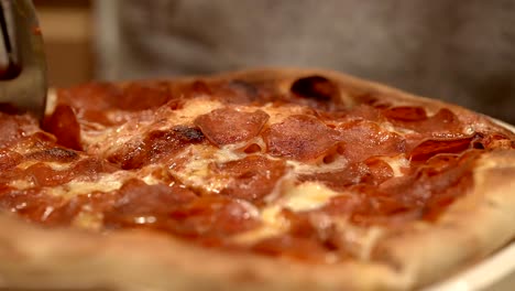 Cutting-fresh-hot-homemade-pepperoni-pizza-into-slices---isolated-close-up-of-the-pizza-wheel
