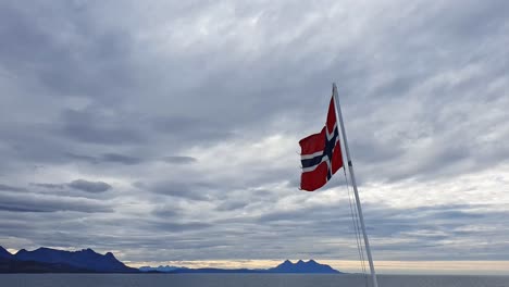 Norwegian-flag-flattering-n-the-wind-against-a-dramatic-cloudy-sky